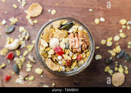 Muesli, muesli in un barattolo di vetro. Una sana prima colazione. Organici di avena con la curcuma, dadi, frutti e bacche. Vista dall'alto. Foto Stock