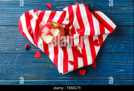 A forma di cuore ad morsi su apple con un panno sul colore tavolo in legno Foto Stock