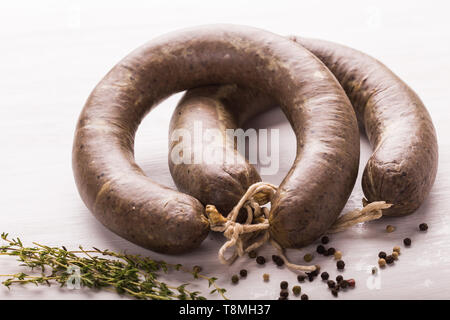 Cibo, carne e deliziosi concetto - Close up di carne di cavallo salsiccia con cumino e pepe su sfondo bianco Foto Stock