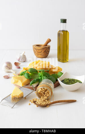 Come preparare il pesto. La tabella con gli ingredienti per la produzione di pesto di basilico. Malta, fresche erbe basilico, pinoli, olio d'oliva, Parmigiano grattugiato, aglio, ciotola con p Foto Stock