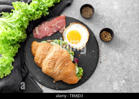 Croissant gustosi sandwich con uovo fritto sulla piastra di ardesia Foto Stock