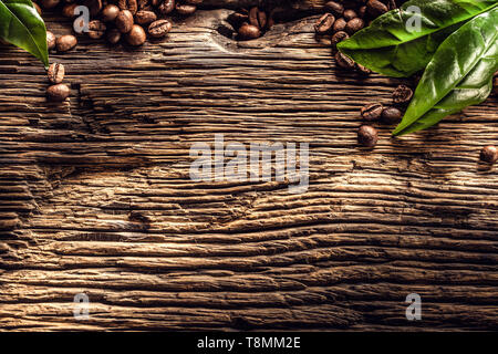Parte superiore di vista i chicchi di caffè e foglie verdi sul rovere rustico tavolo Foto Stock