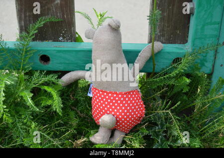 Cucite a mano fatto a mano e simpatico e divertente orsacchiotto di peluche che indossa punteggiata rossa pantaloni in un giardino estivo. Realizzato da vestiti vecchi, stracci e scarti. Foto Stock