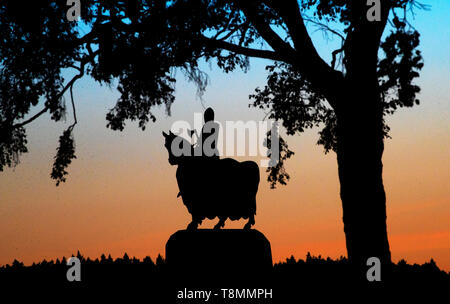 Il sole tramonta dietro la statua di Robert the Bruce sul suo cavallo di guerra nella Battaglia di Bannockburn sito nelle vicinanze di Stirling. Foto Stock