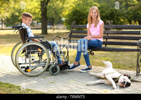 Ragazzo disabile con sua sorella e cane appoggiato in posizione di parcheggio Foto Stock