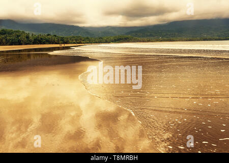 Caldo tramonto a Uvita beach in Costa Rica con il riflesso del cielo in acqua poco profonda Foto Stock