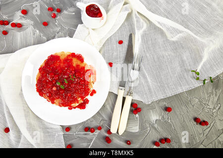 American pancake con la marmellata - berry, pallon di maggio, mirtillo rosso su sfondo grigio. Pancake fatti in casa con salsa di frutti di bosco e le foglie di menta. Sana colazione con prodotti freschi h Foto Stock