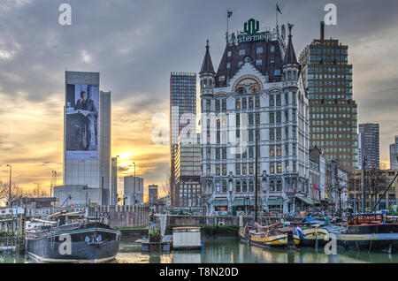 Rotterdam, Paesi Bassi, 7 Dicembre 2016: storico chiatte nel porto vecchio e storico grattacielo della Casa Bianca al tramonto Foto Stock