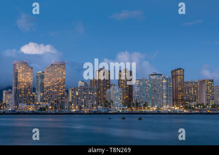 Luci della città intorno Ala Wai del porto al crepuscolo da Ala Moana Beach Park, Oahu, Hawaii. Foto Stock