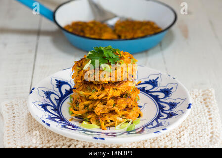 Uno stack di quattro patata dolce e carota rostis su un blu e bianco piastra. Foto Stock