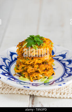 Uno stack di quattro patata dolce e carota rostis su un blu e bianco piastra. Foto Stock