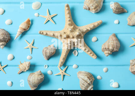 Molte stelle marine e conchiglie sul colore di sfondo in legno, primo piano e vista dall'alto. La vacanza estiva sfondo Foto Stock