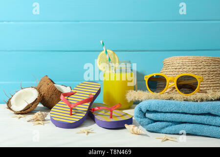 La vacanza estiva accessori sul tavolo bianco contro il colore di sfondo di legno, lo spazio per il testo. Vacanze felici Foto Stock