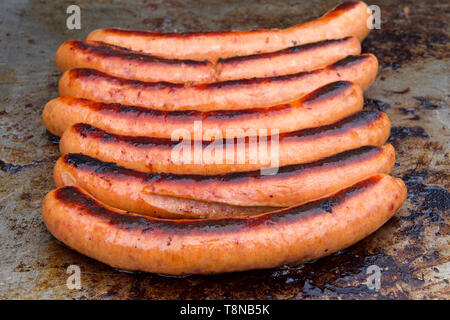 Close up su grandi salsicce la frittura su un grill all'aperto. Popolari street fair cibo. Foto Stock