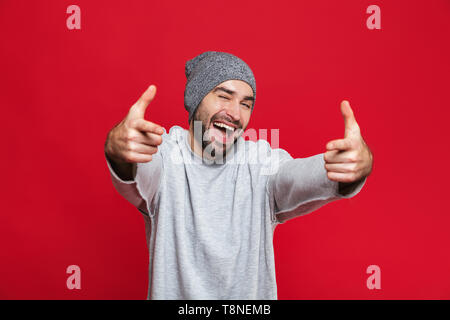 Immagine dell uomo sorridente 30s con la barba e baffi denti rivolti a voi mentre in piedi isolato su sfondo rosso Foto Stock