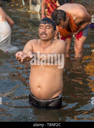Uomo compie il rituale puja preghiera nel fiume Gange, Varanasi, India Foto Stock