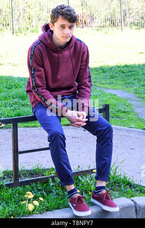 Il giovane uomo si siede guardando in lontananza. Un giovane uomo di pensiero al di fuori. Mi siedo sui gradini, guardo la distanza, credo Foto Stock