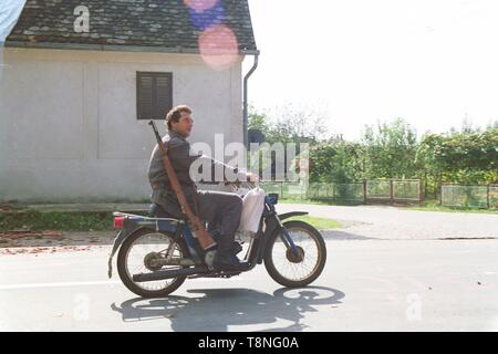 Un poliziotto croato, armati per la guerra i capi su un motociclo per il front-line nel villaggio di Moscenica durante la disgregazione della Jugoslavia nel 1991-1992. Foto di Adam Alexander Foto Stock