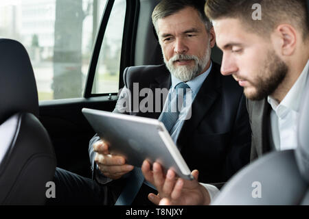 Colleghi di lavoro per discutere idee di business mentre sedendo nel sedile posteriore di auto o taxi. Foto Stock