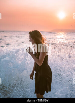 Le onde del mare gli schizzi sulla donna in spiaggia Foto Stock
