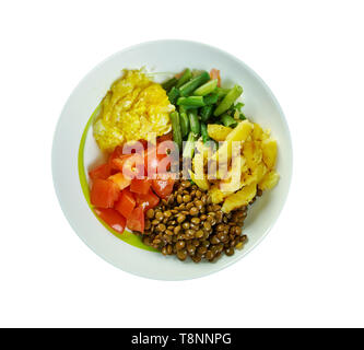 Sunshine ciotole di lenticchie con aglio olio di oliva medicazione, fagioli verdi, pomodori, erbe, di patate arrosto, lenticchie, formaggio di capra e soffici uova strapazzate Foto Stock