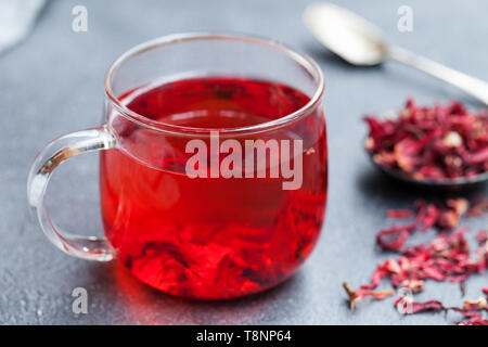 Hibiscus tè in tazza di vetro. Sfondo grigio. Close up. Foto Stock