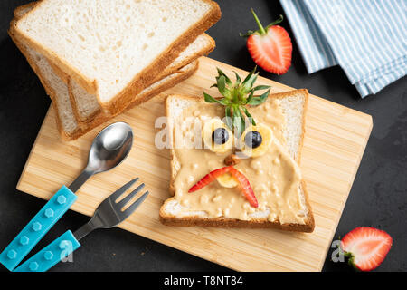 Burro di arachidi toast per bambini. Faccia buffa decorazione su colazione o pranzo PB toast. Pasto per bambini. Vista superiore Foto Stock