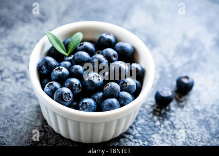 I mirtilli in una ciotola. Appena raccolto mietuto i mirtilli in ceramica bianca bowl, primo piano Foto Stock