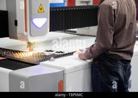 Operaio industriale operano CNC macchine taglio laser di taglio di foglio di metallo Foto Stock