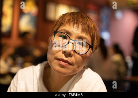 Matura donna Taiwanese di etnia cinese seduto in un ambiente caldo e accogliente ristorante Foto Stock