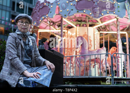 Moda Donna Taiwanese di etnia cinese seduto con le giostre in background Foto Stock