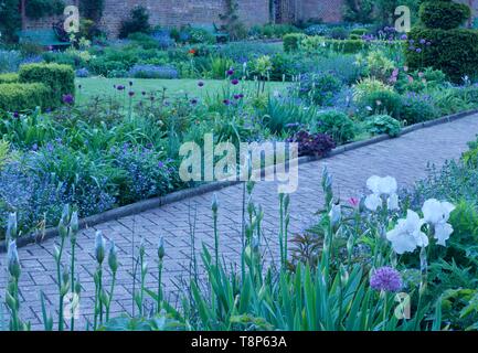 Grazioso giardino murato con lussureggianti aiuole e percorso attraverso il centro Foto Stock