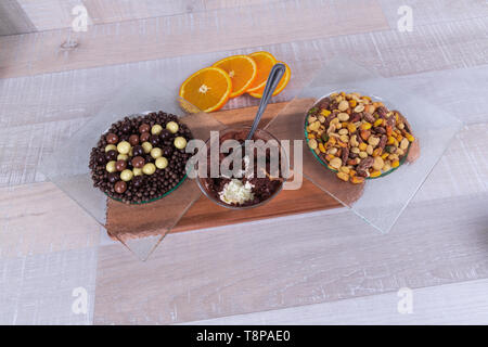 Mousse al cioccolato, una ciotola di noci e cioccolato dei cereali su un tavolo di legno Foto Stock