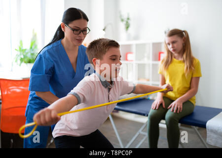 Grave giovane ragazzo in formazione con corda sportiva mentre medico Foto Stock