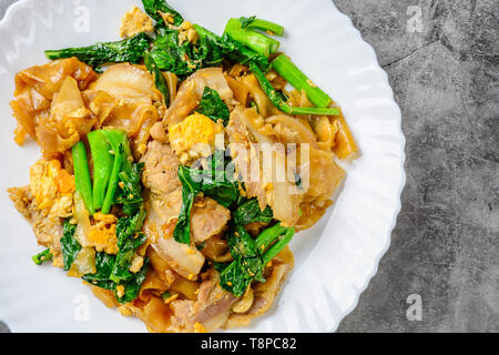 Saltati in padella il riso fresco-farina Tagliatelle con carne di maiale tagliata a fette, uovo e Kale. Quick noodle friggere. Foto Stock