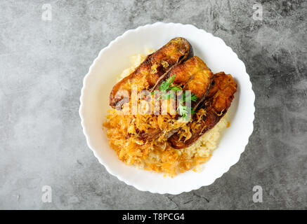 Fritte tagliate a fette Pangasius pesce con aglio, servito con riso marrone. Foto Stock