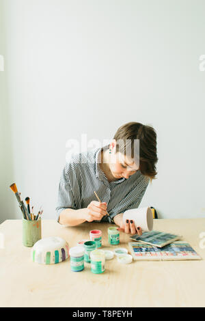 La ceramica donna tiene in mano una tazza di dipingere l'ornamento, di ceramica fatti a mano Foto Stock