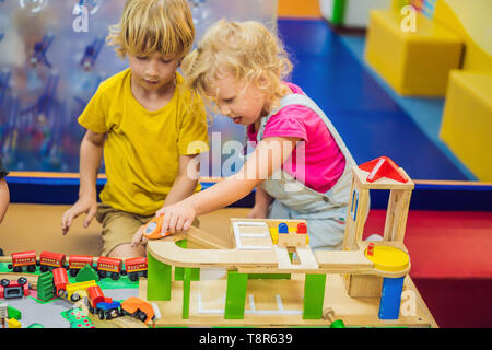 Bambini che giocano con treni di legno. Il Toddler kid e il bambino gioca con blocchi, treni e automobili. Giocattoli educativi per la scuola materna e asilo bambino. Ragazzo Foto Stock