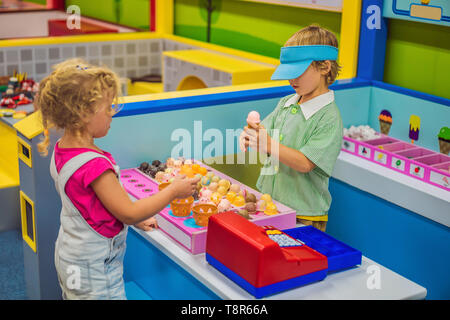 Un ragazzo e una ragazza a giocare nella cucina giocattolo, rendendo toy gelato Foto Stock