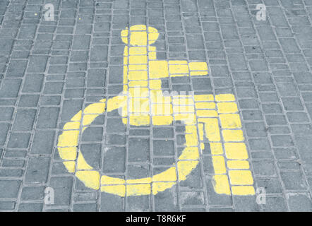 Lo spazio di parcheggio delle auto per disabili il segno disegnato sulla piastrella su strada. Foto Stock