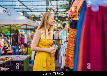 Vendita, Vendita al dettaglio, negozi e concetto di abbigliamento - donna sceglie i vestiti nel mercato asiatico Foto Stock