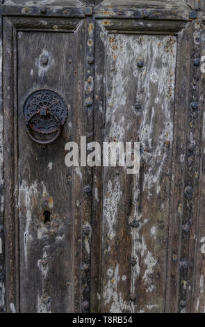 Antica porta di legno. Porta ha bella black metal borchia modellata e costellata di disegno. Mostra grande texture in il legno vecchio e un grande buco della serratura tagliare int Foto Stock