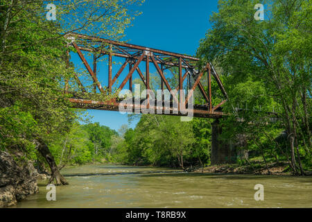 Vecchio treno arrugginito traliccio su una veloce che scorre il fiume Foto Stock