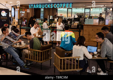 I clienti si vede a bere caffè presso la multinazionale americana la catena Starbucks Coffee ristorante a Hong Kong. Foto Stock