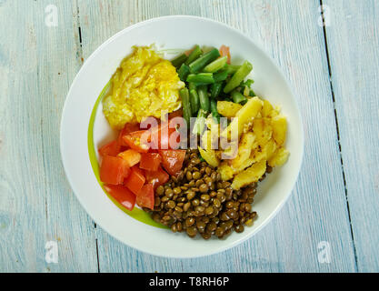 Sunshine ciotole di lenticchie con aglio olio di oliva medicazione, fagioli verdi, pomodori, erbe, di patate arrosto, lenticchie, formaggio di capra e soffici uova strapazzate Foto Stock