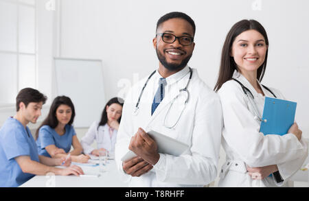 Due medici In Camici in posa per la fotocamera a una conferenza Foto Stock