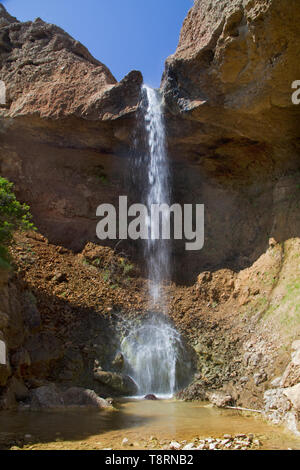 Una piccola cascata schizzi in basso in una piccola piscina in un roccioso verticale Foto Stock