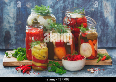 Colorato conservato e marinata di verdure di stagione con le erbe sul legno rustico tavolo da cucina Foto Stock