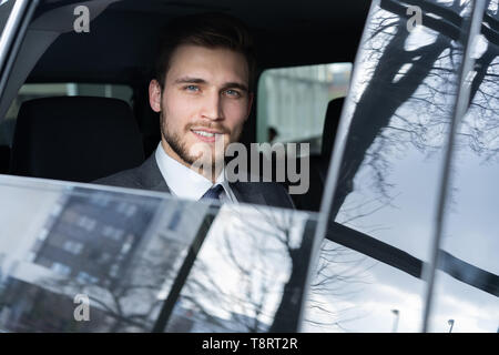 Giovane imprenditore bello è seduto in auto di lusso Foto Stock