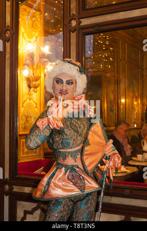 Il Carnevale di Venezia, persona in posa di fronte del Caffè Florian, San Marco di notte con una visione all'interno del caffè attraverso la finestra, Venezia, vene Foto Stock